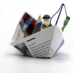 Melange de Legographie et d'origami representant un bateau. Cette Legographie represente un bateau de pêcheur en origami et une minifigure de Lego pêcheur.