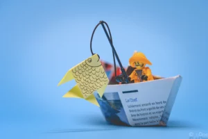 Cette Legography, le photographe a mis en scène un bateau en origami et un lego qui pêche un poisson en origami.