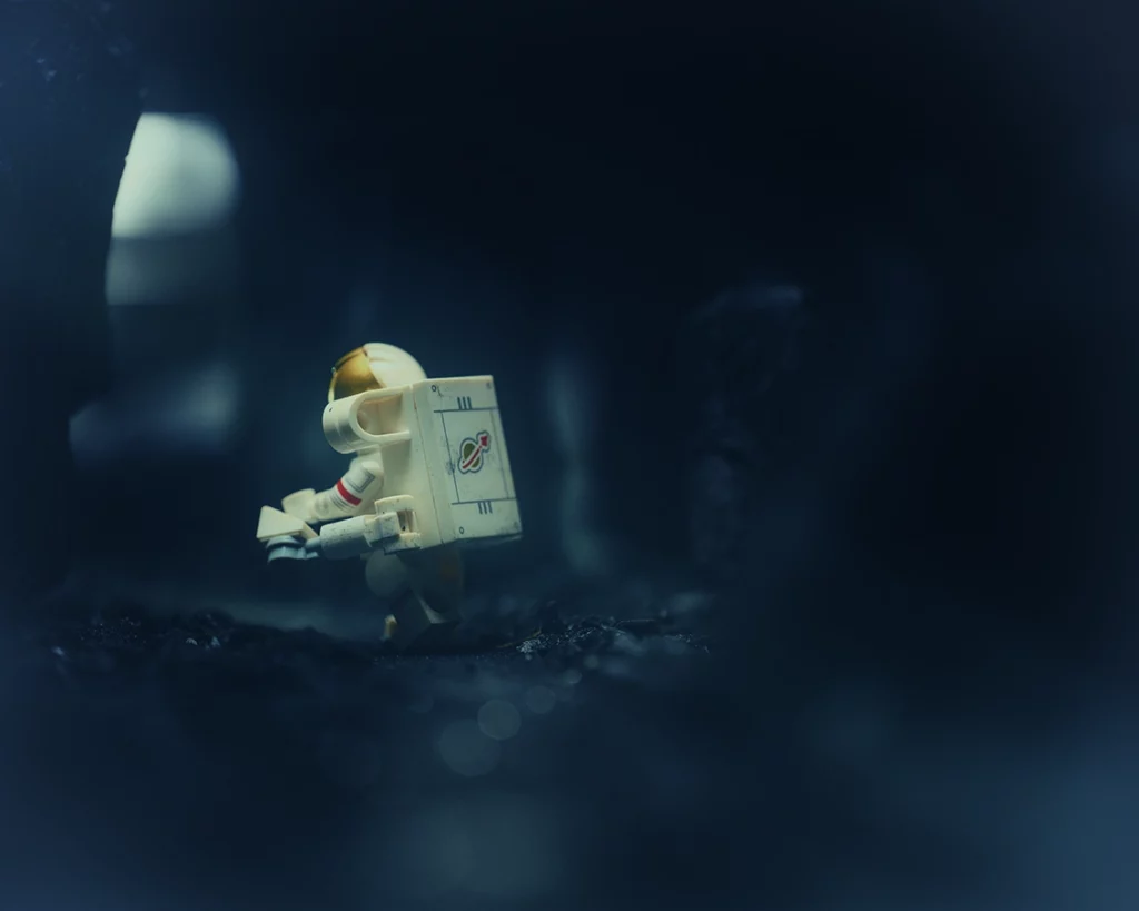 alt="Minifigure cosmonaute LEGO marchant sur un sol extraterrestre noir en charbon"